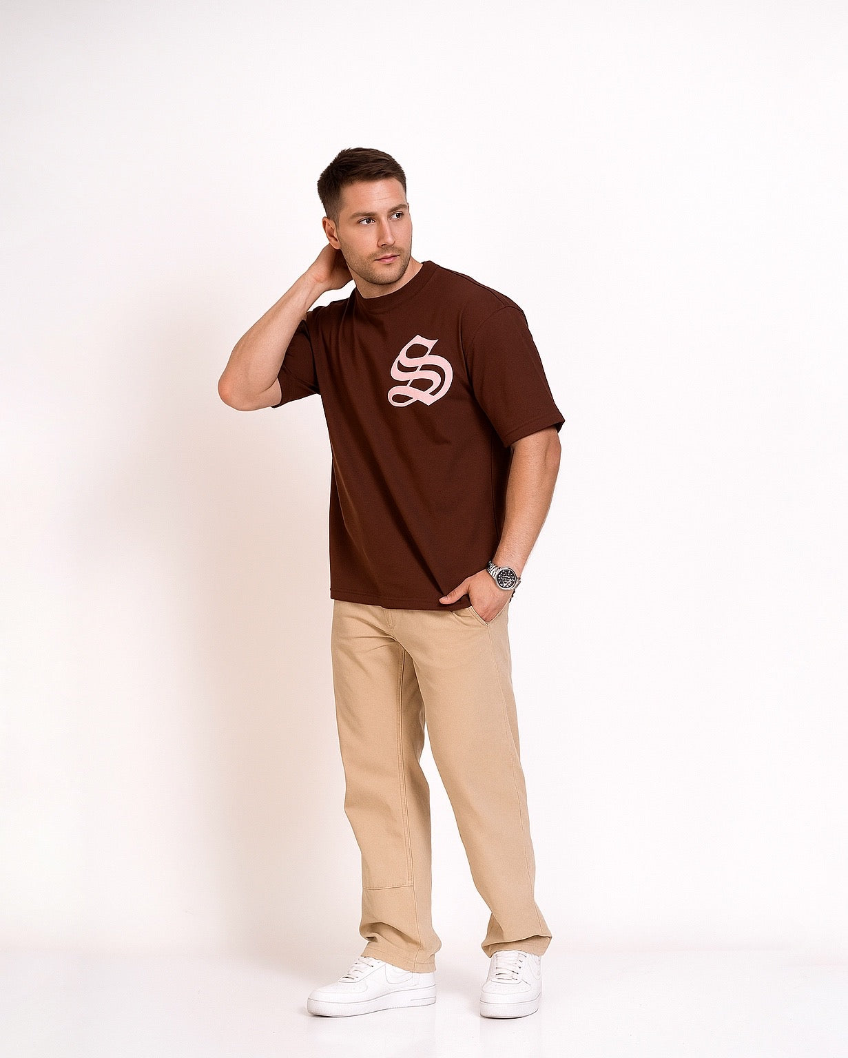 Man wearing STRADA Vintage Oversized Crew Neck brown t-shirt with a logo and beige pants on a white background